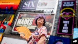 ARCHIVO - Una guía turística se abanica mientras trabaja en Times Square mientras aumentan las temperaturas, el 27 de julio de 2023, en Nueva York.