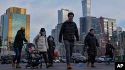 行人穿越北京中心商務區辦公大樓附近的交通路口。（2024年2月8日）