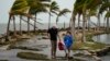 Bob Givehchi, izquierda, y su hijo Daniel, de 8 años, residentes de Toronto que visitan Miami por primera vez, caminan entre escombros y palmeras arrastradas por ráfagas de viento, en Matheson Hammock Park en Coral Gables, Florida, el viernes 15 de diciembre de 2023. 