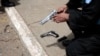 ARCHIVO - Un oficial de policía sostiene un arma mientras otra arma yace en el piso durante una investigación criminal en la Ciudad de Guatemala.