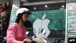 一名越南女子在河內騎電動車路過一家蘋果專賣店。（2012年9月28日）