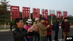 中國福建廈門豎立起一個台灣金門島可以看到的「一國兩制統一中國」的大型標語牌,旅遊者在前拍照。 (2024年1月12日)