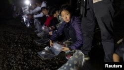 2023年4月3日美國德州弗龍頓: 一名從墨西哥格蘭德河偷渡進入美國的中國婦女將自己的物品放入塑膠袋