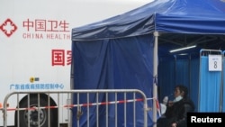香港東涌居民在接受新冠病毒核酸檢測，後面的車輛是中國廣東省疾病預防控制中心的移動測試車。（2022年2月21日）