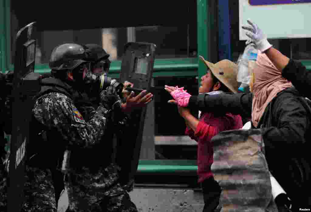 Demonstrators face security forces during a protest against Ecuador's President Lenin Moreno's austerity measures in Quito, Ecuador.
