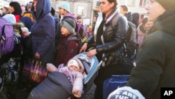 Refugiados con niños esperan un transporte después de huir de la guerra desde la vecina Ucrania en una estación de tren en Przemysl, Polonia, el 24 de marzo de 2022.