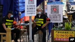 兩名執勤保安在北京一個居民小區外檢查居民需要出入小區的健康碼。（2022年11月9日）