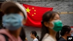 2022年10月1日，北京國慶假期的第一天，人們走在懸掛中國國旗的一條旅遊購物街上。