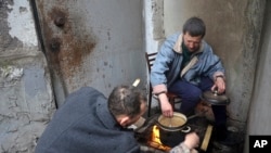 Los residentes de Mariúpol cocinan sentados en la entrada de su edificio de apartamentos dañado en un área de la ciudad que los separatistas respaldados por Rusia afirman controlar en la ciudad ucraniana de Mariúpol, el 13 de abril de 2022.