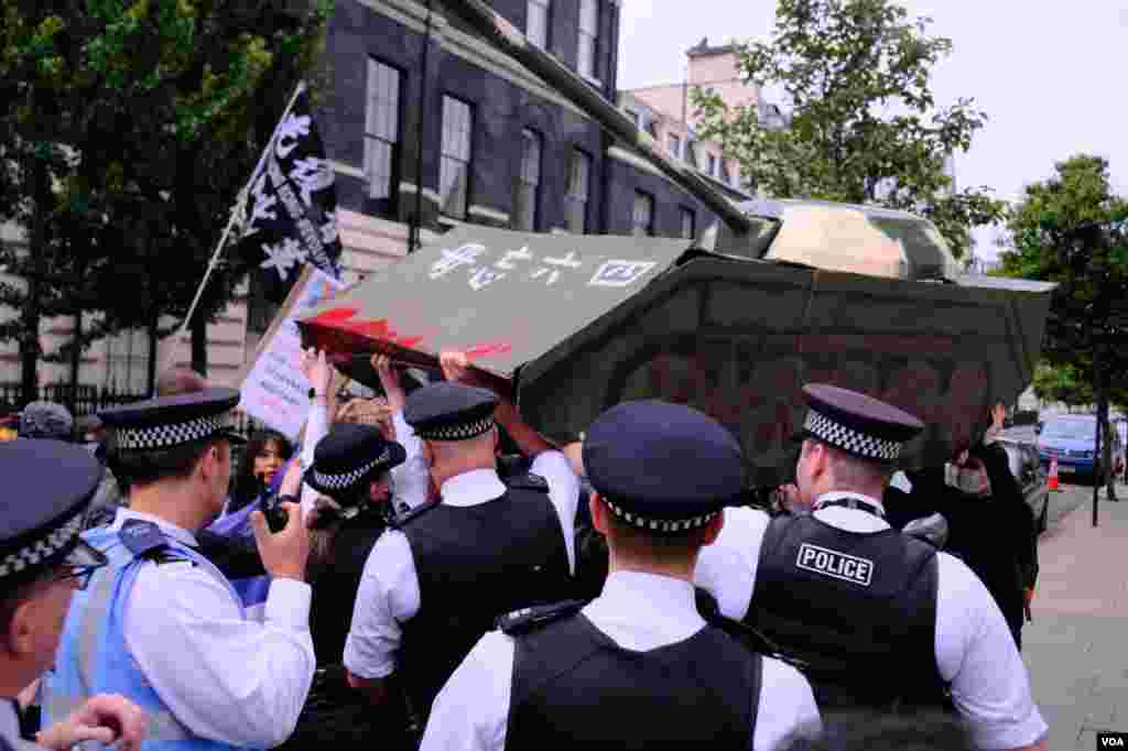 2022年6月4日，倫敦警察在中國駐英國大使館外阻止示威者抬著的紙紮坦克走近大使館範圍。（美國之音鄭樂捷） 