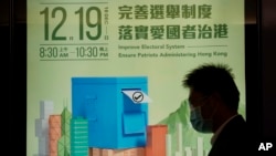一名男子走過一幅有關香港立法會選舉的宣傳海報（2021年11月23日）