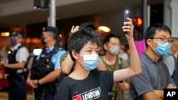 2022 年 6 月 4 日星期六，支持民主的抗議者在香港維多利亞公園附近手持發光的手機。