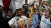 Syrian protesters shout slogans as they burn a poster of Syrian President Bashar Assad, left, and his father Hafez Assad during a demonstration in front of the Syrian embassy, in Nicosia, Cyprus, April 22, 2011. 