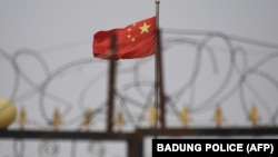 資料照片：中國國旗在新疆喀什南部地區一處建築物的圍欄鐵絲網後飄揚。 （2019年6月4日）