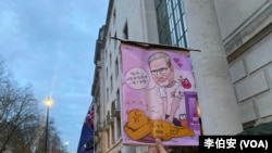 港人Moses Ng舉起諷刺習近平和工黨首相的漫畫，表達對英國工黨政府對華政策的失望。（李伯安/美國之音）