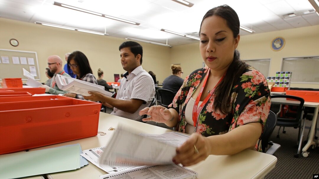 FILE -Bianca Savola, an election clerk at the Sacramento County Registrar of Voters, inspects mail-in ballots in Sacramento, Calif., May 30, 2018.