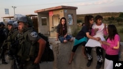 Israeli settlers play next to Israeli border police in Tapuah junction, near the West Bank city of Nablus, April 30, 2013.