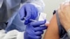 FILE - A man receives a shot in the first-stage safety study clinical trial of a potential vaccine for COVID-19, the disease caused by the new coronavirus, at the Kaiser Permanente Washington Health Research Institute in Seattle, March 16, 2020..