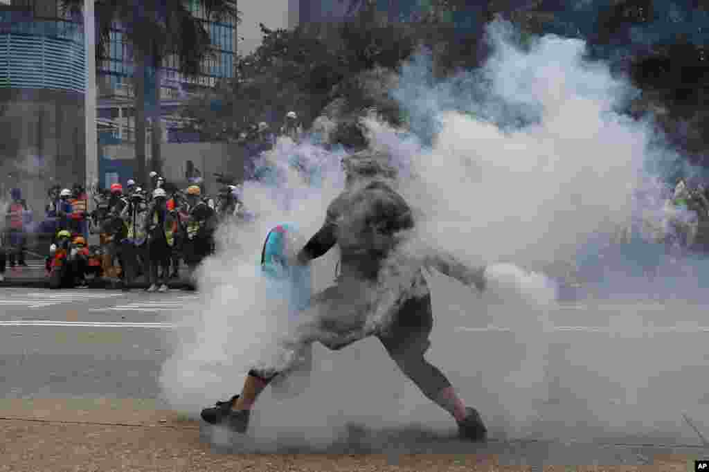 A protester throws a tear gas round back at police during the demonstration in Hong Kong.