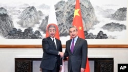 中國官媒新華社發佈的照片​​顯示，中國外交部長王毅在北京與到訪的日本外務大臣岩屋毅握手(2024年12月25日)。