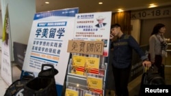 在香港亞洲國際博覽館，一名來自中國的學生在參加SAT考試後，在海外教育廣告橫幅後用手機通話。 (2013年11月2日)