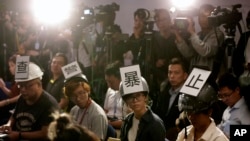 多位香港記者在2019年11月4日頭戴“查警暴止警謊”標語的頭盔等候警方舉行記者會。