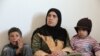 A Syrian woman at home with two of her children inside their apartment in the city of Mafraq, in Northern Jordan. Her husband has remained in Syria.