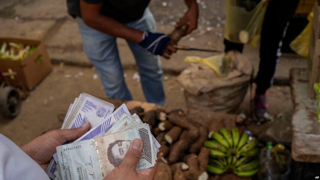 Foto de archivo. Un vendedor cuenta bolívares y billetes de dólares estadounidenses en un mercado público en el barrio Quinta Crespo en Caracas, Venezuela. (Foto AP/Matías Delacroix)