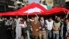 Jordanian supporters of the Islamic Action Front carry a giant Jordanian flag as they demand for political reforms during a protest in Amman, March, 4, 2011.