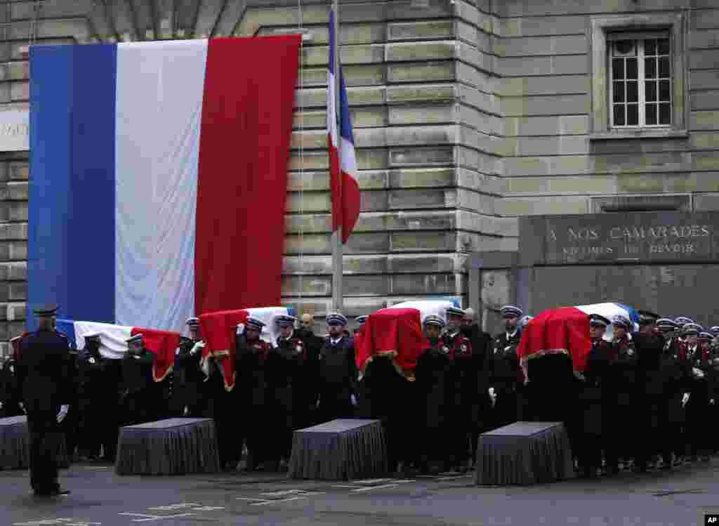 Police officers carry the coffins of the four victims of last week's knife attack during a ceremony in the courtyard of the Paris police headquarters. France's presidency said the victims will be posthumously given the country's highest award, the Legion of Honor.