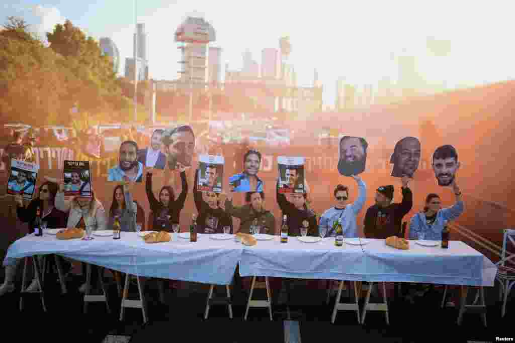 People sitting at a table representing the Friday dinner table in the Jewish tradition hold up images of hostages kidnapped during the deadly Oct. 7, 2023 attack, as supporters block a road to demand the release of their loved ones in Tel Aviv, Israel. REUTERS/Itai Ron ISRAEL OUT