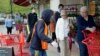 Doorman Dilon Moore, center, helps with shopping carts and controls the number of customers allowed to shop at one time at a Trader Joe's supermarket in Omaha, Neb., May 7, 2020. 