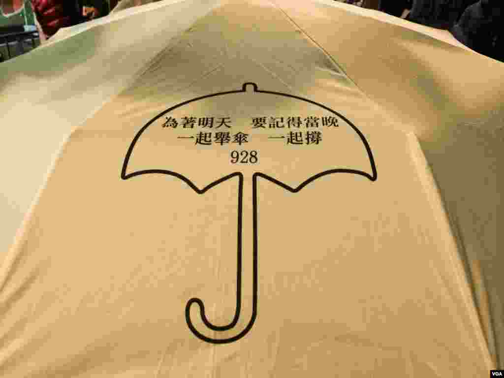 有香港市民撐著印有雨傘運動標誌的黃色雨傘,參加平安夜遊行