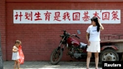 資料照：一個媽媽和孩子在「計劃生育是我國基本國策」的標語前走過。（2002年7月23日）