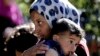 Syrian refugee girl carries her sister, as she listens to the United Nations High Commissioner for Refugees, UNHCR, chief Antonio Guterres, not seen, during his visit to a Syrian refugee camp, in Ketermaya village southeast of Beirut, Lebanon. (File photo
