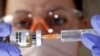 FILE - A woman holds a small bottle labeled with a 'Vaccine COVID-19' sticker and a medical syringe in this illustration taken April 10, 2020.