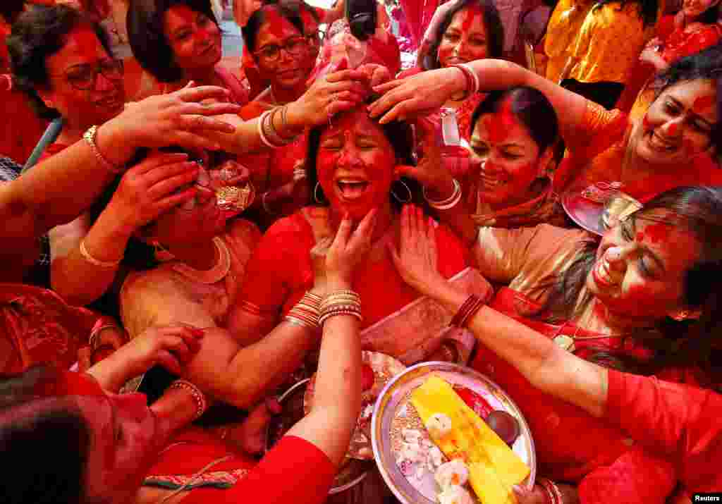 A Hindu woman reacts as "Sindhur," or vermillion powder, is applied to her face after worshipping an idol of the Hindu goddess Durga on the last day of the Durga Puja festival in Chandigarh, India.