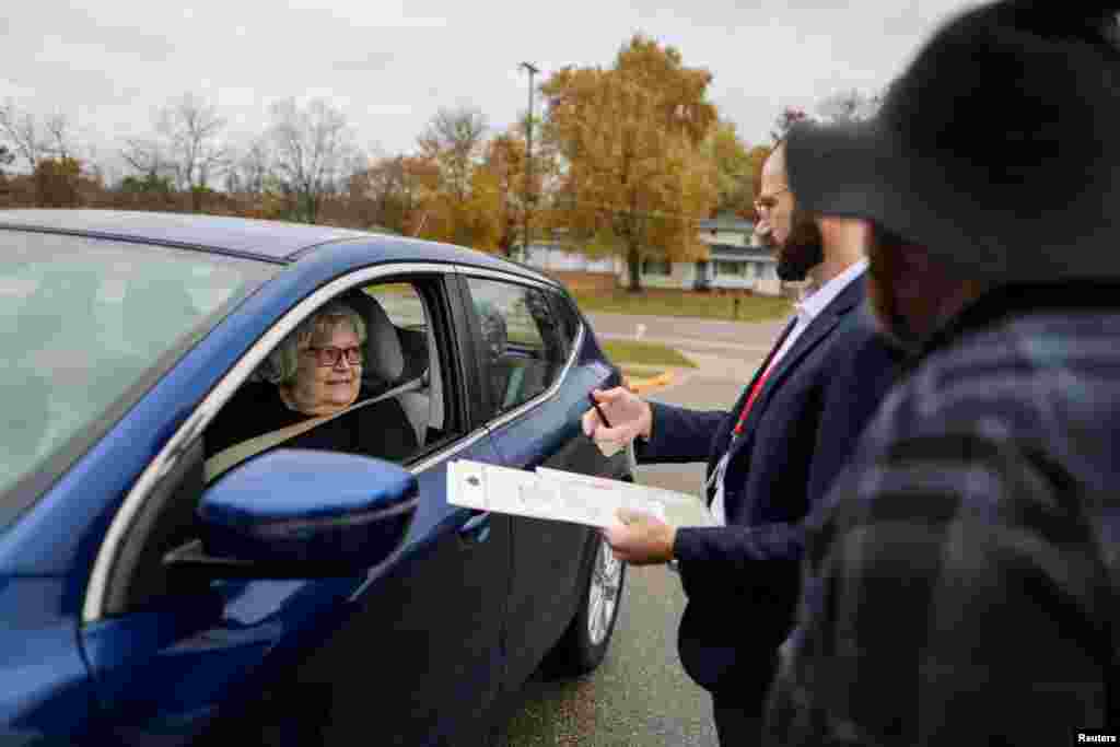 Funcionários eleitorais Owen O'Keefe e Brandon Rieckhoff ajudam Mary Miller, com problemas de mobilidade, no processo de votação à porta da Faith Lutheran Church em Grand Rapids, Michigan, a 5 de novembro de 2024.