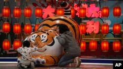 北京一家商場設立的卡通老虎迎接虎年春節，一對母子圍著卡通老虎做遊戲。 （2022年1月9日）