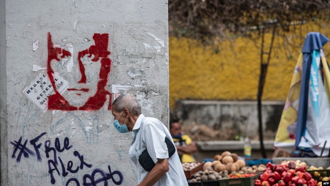 Un hombre pasa junto a un grafiti que exige la libertad del empresario colombiano Alex Saab, en Caracas, el 23 de febrero de 2021. 