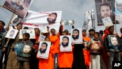 Yemeni protesters hold pictures of people in U.S. detention at a demonstration outside the U.S. Embassy in Sanaa, Yemen, demanding the release of Yemeni detainees in the Guantanamo Bay detention facility, Saturday, Jan. 11, 2014. AP Photo/Hani Mohammed