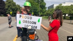 A reporter interviews logger Bridger Hasbrouck, of Dallas, Ore., in Salem, Ore., June 20, 2019, the day the Senate was to take up a bill creating a cap-and-trade program to curb carbon emissions. Senate Republicans, however, walked out, preventing a vote on House Bill 2020.