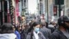 FILE - A pedestrian wears a surgical mask on a busy street as concerns grow around COVID-19, in Manhattan, New York, March 3, 2020. 
