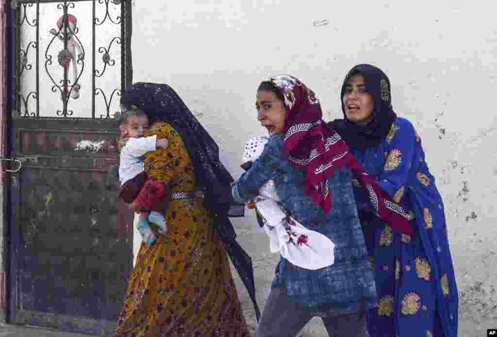 People run to take cover after mortars fired from Syria, in Akcakale, Turkey. An Associated Press journalist said at least two government buildings were hit by the mortars in Sanliurfa province's border town and at least two people were wounded.