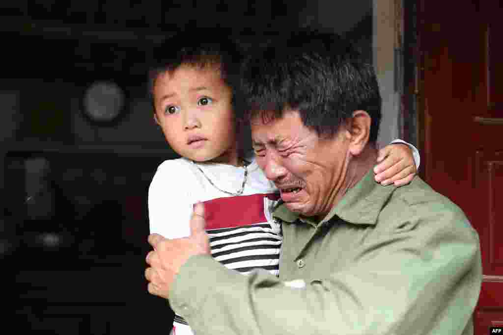 Le Minh Tuan, father of 30-year old Le Van Ha, who is feared to be among the 39 people found dead in a truck in Britain, cries while holding Ha's son outside their house in Vietnam's Nghe An province.
