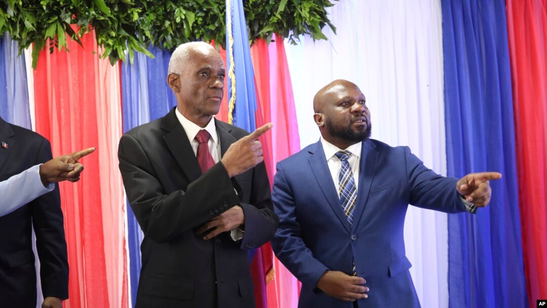 Edgard Leblanc Fils, a la izquierda, y Smith Augustin se preparan para una foto de grupo con el consejo de transición después de que Fils fuera nombrado presidente del organismo. En Puerto Príncipe, Haití, el martes 30 de abril de 2024. 
