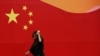 一名戴口罩的妇女经过一面画着中国国旗的墙。（资料照片）