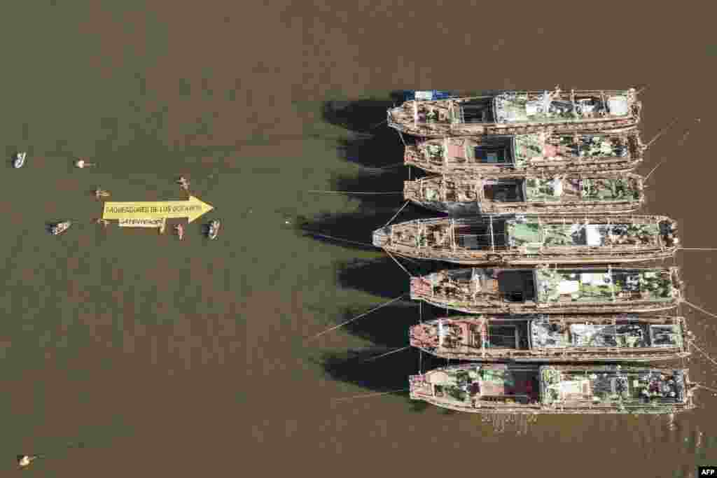 In this aerial handout picture released by Greenpeace, activists of the non-governmental environmental organization display a 25-meter-long arrow that reads ‘Looters of the Oceans’ pointing to South Korea's fishing vessels Agnes 103 y Agnes 107 anchored at the port of Montevideo, Uruguay.