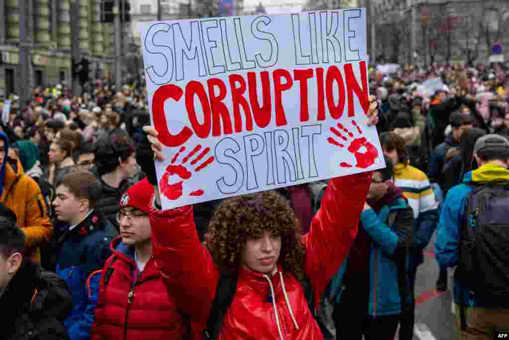 A woman holds a placard reading "Smells like corruption spirit" during a demonstration in central Belgrade on Jan. 24, 2025, after student protest organizers called for a general strike over the fatal collapse of a train station roof in November. (Photo by Andrej ISAKOVIC / AFP)