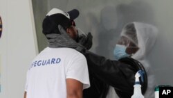Rafael Ruiz, left, is tested for COVID-19 at a walk-up testing site during the coronavirus pandemic, July 17, 2020, in Miami Beach, Fla. 